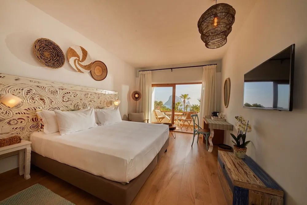 Heller Schlafbereich mit großem Doppelbett, Schreibtisch und Balkontür mit Blick aufs Meer.