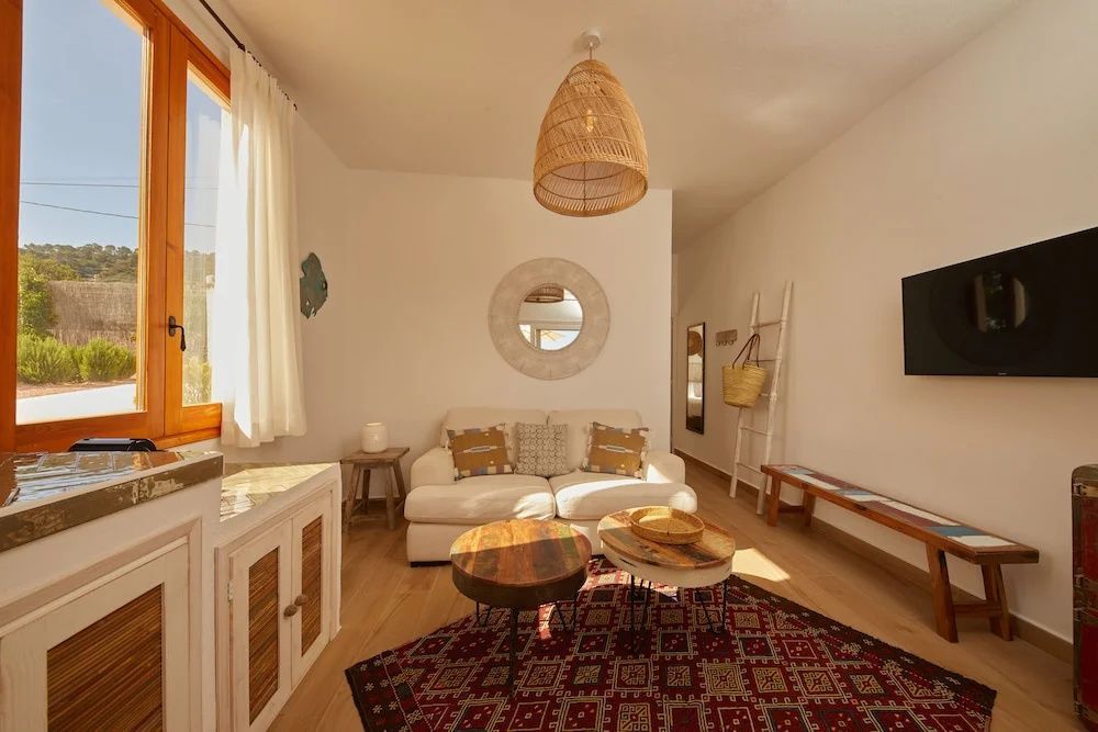 Wohnzimmer mit weißem Sofa, zwei Holzbeistelltischen und einem runden Wandspiegel.