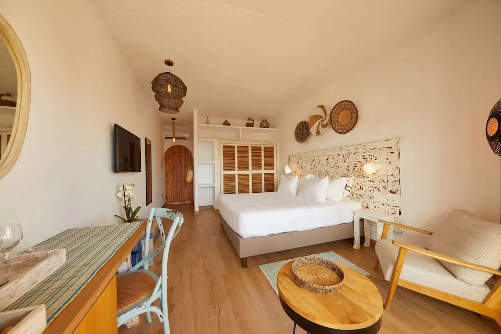 Modern eingerichtetes Hotelzimmer mit Doppelbett, Holzmöbeln und Blick Richtung Eingangsbereich.