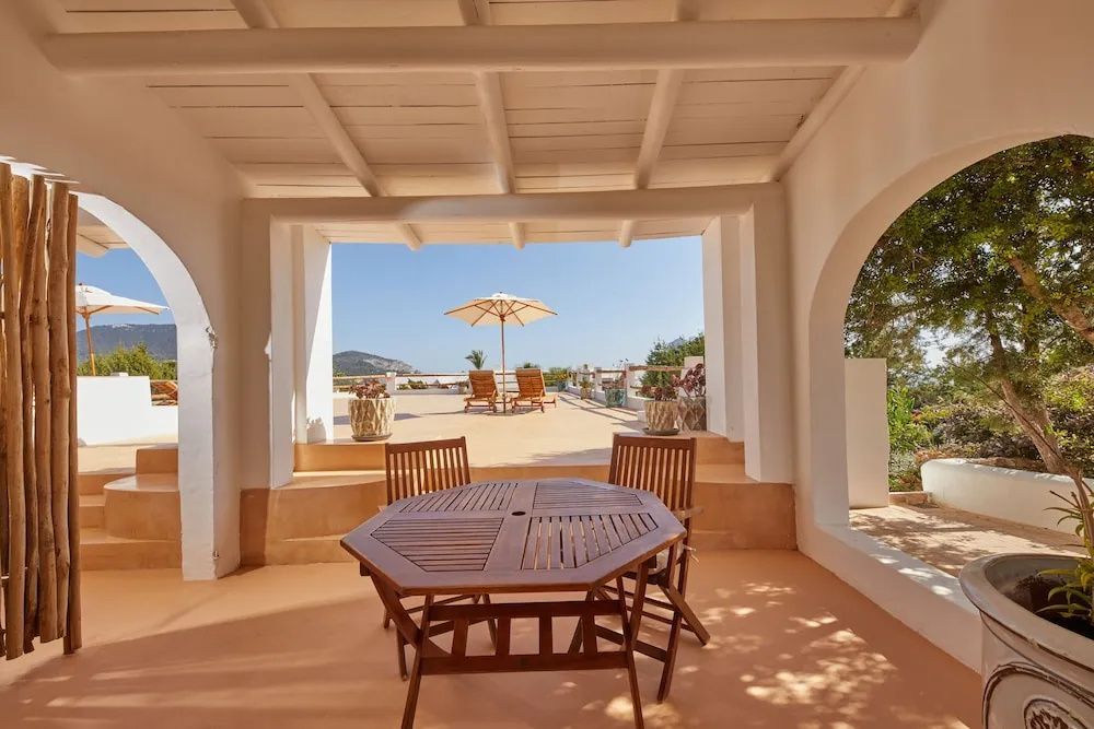 Überdachte Terrasse mit Holztisch und Blick auf ein weitläufiges Sonnendeck.