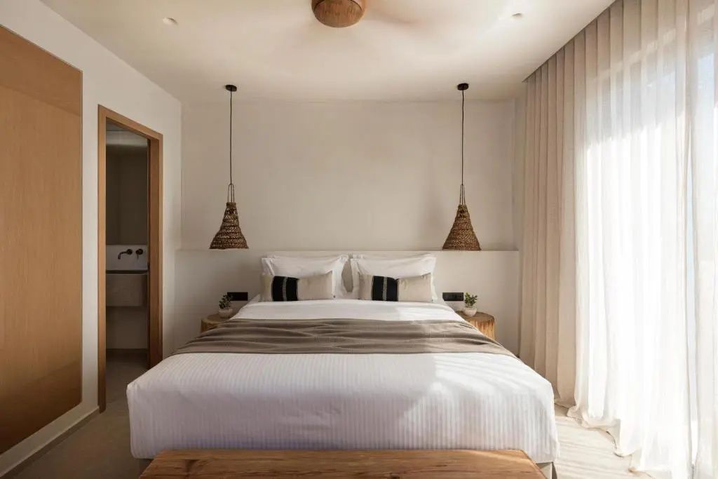 Doppelbett in minimalistisch gestaltetem Hotelzimmer mit zwei Hängelampen.