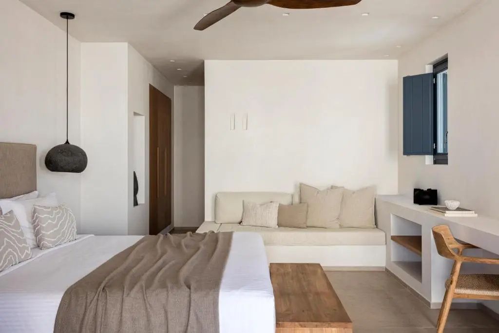 Schlafbereich mit Doppelbett, beigefarbenem Sofa und Holzmöbeln.