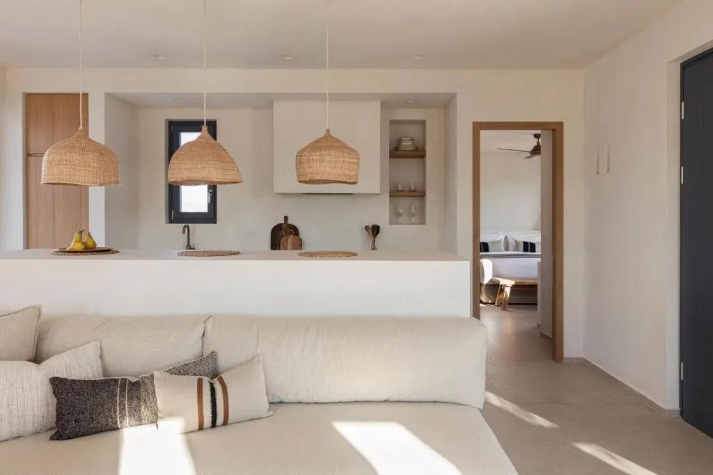 Offener Wohnbereich mit hellem Sofa, geflochtenen Lampenschirmen und Blick ins Schlafzimmer.