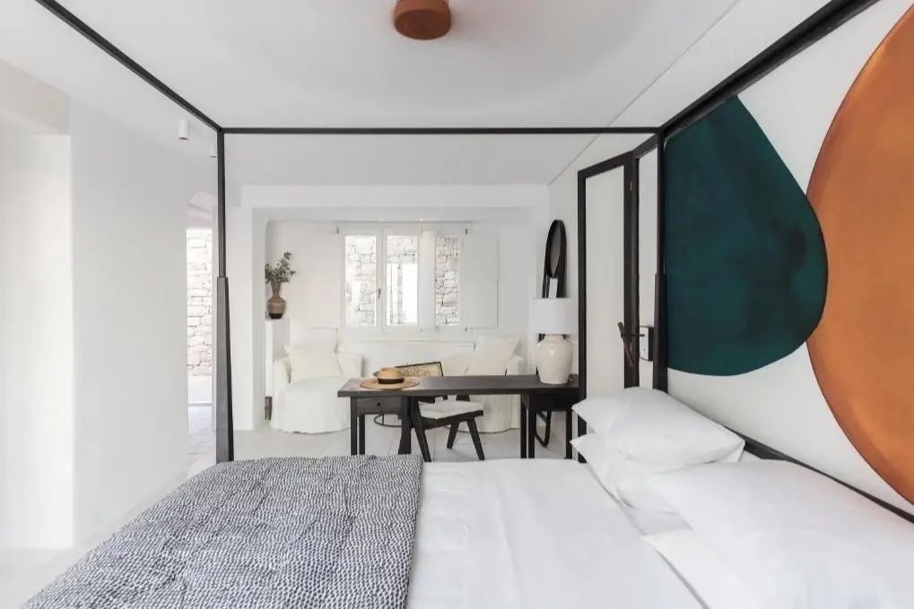Schlafbereich mit schwarzem Himmelbett, Schreibtisch und zwei weißen Sesseln.
