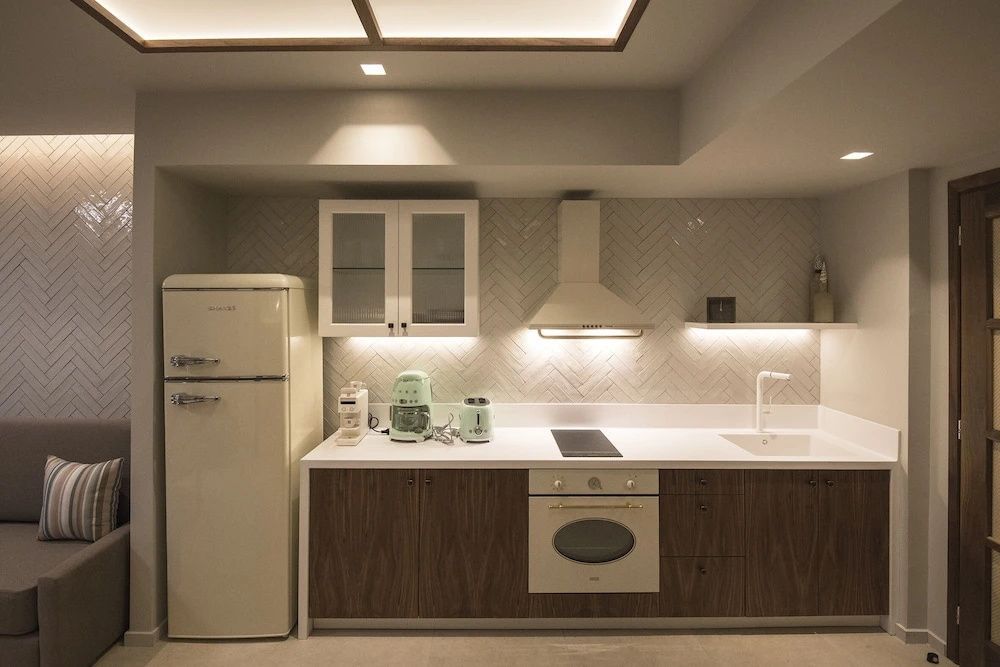 Moderne Küchenzeile mit Holzfronten, hellem Kühlschrank und hellgrünen Küchengeräten.