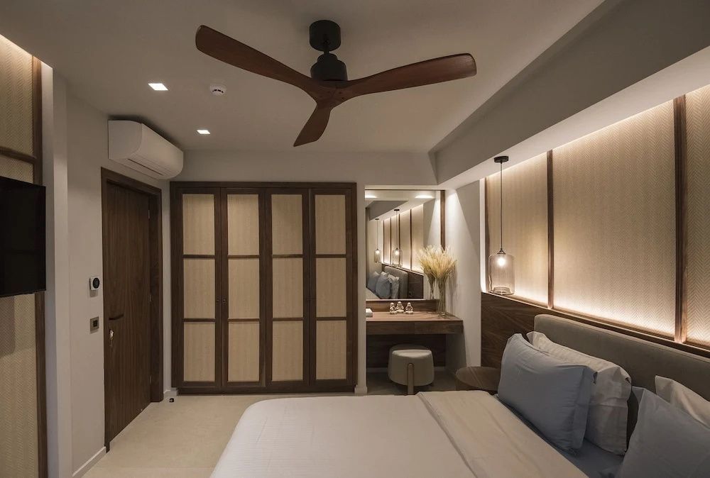 Schlafbereich mit Blick auf einen Holzschrank, Schminktisch mit Spiegel und Deckenventilator.