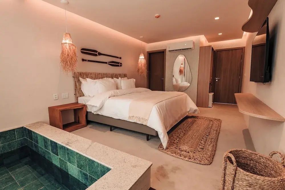 Zimmer mit Doppelbett, Wanddekoration aus Paddeln, einem Wandspiegel und einem eingelassenen Becken.