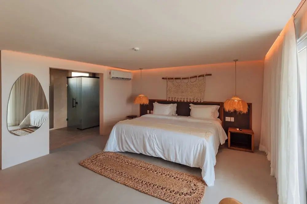 Geräumiges Schlafzimmer mit großem Doppelbett, Flechtlampen und sanfter Beleuchtung.