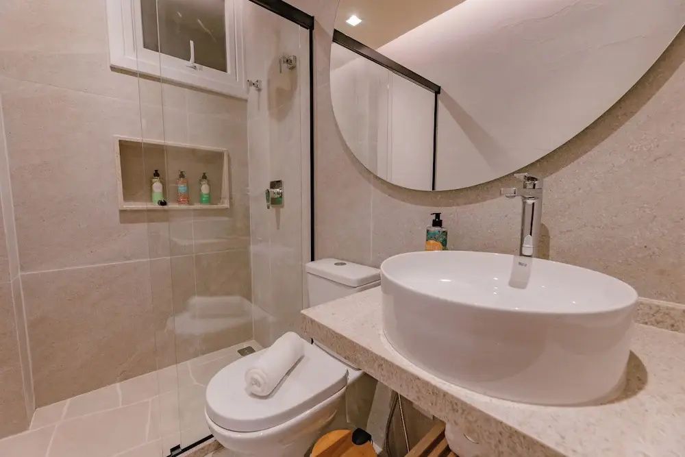 Modernes Badezimmer mit Glasdusche, Aufsatzwaschbecken, Spiegel und Toilette.