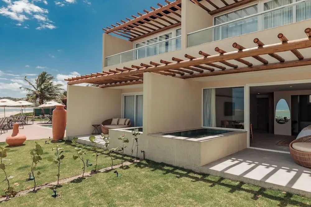 Moderne Außenfassade mit Terrassen, Holzpergola, kleinen Whirlpools und Rasenfläche.