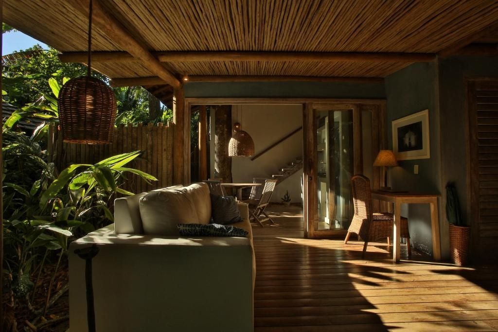 Wohnbereich einer Suite mit hellem Sofa, Holzfußboden und Strohdecke.