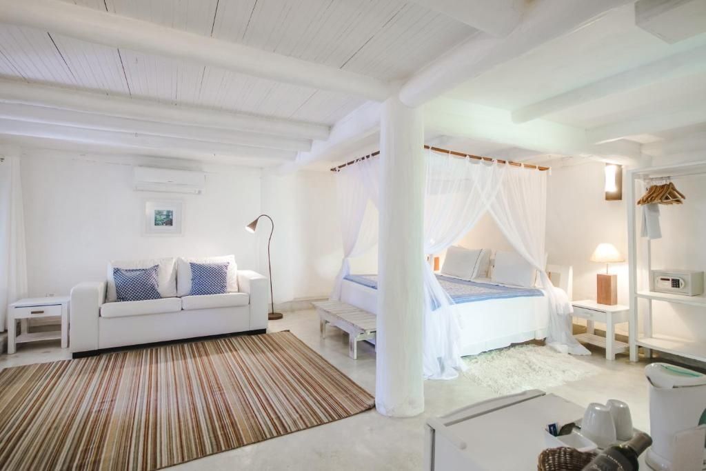 Geräumiges Zimmer mit weißem Himmelbett, hellem Sofa und Teppich.