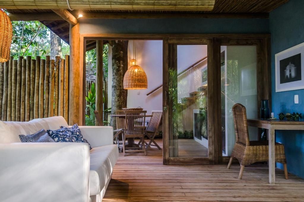Überdachte Holzterrasse mit weißem Sofa und Blick auf den Essbereich der Unterkunft.
