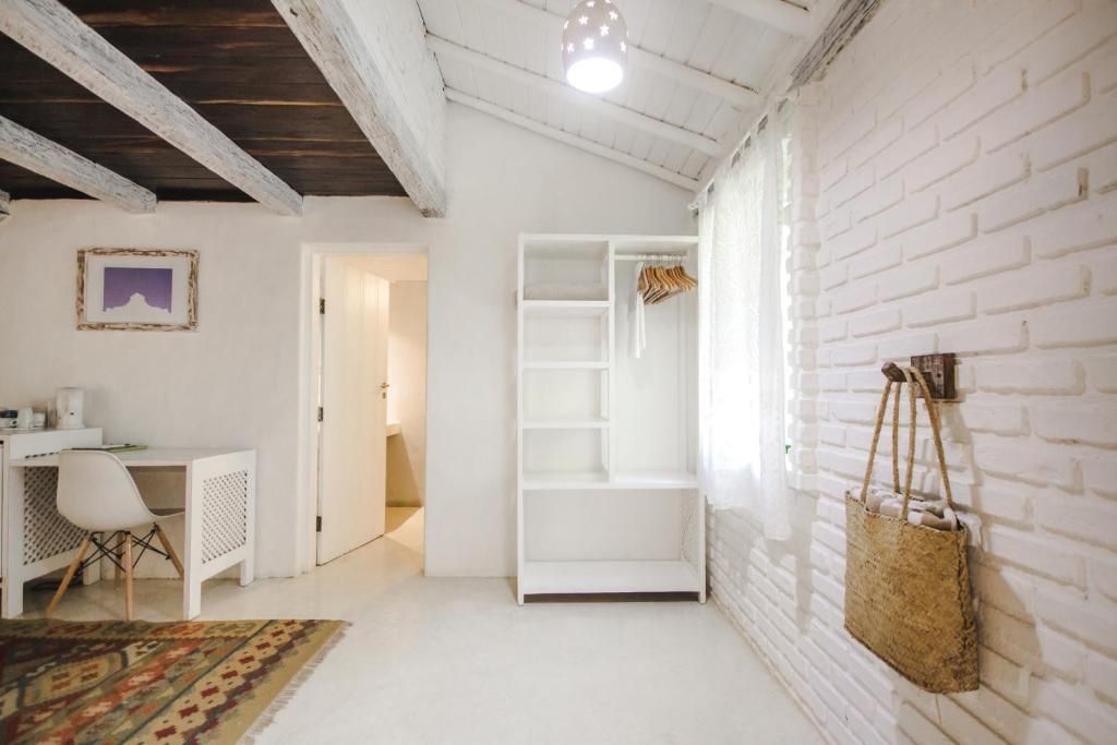 Helles Zimmer mit weiß gestrichener Backsteinwand, offenem Regalschrank und Holzdeckenbalken.