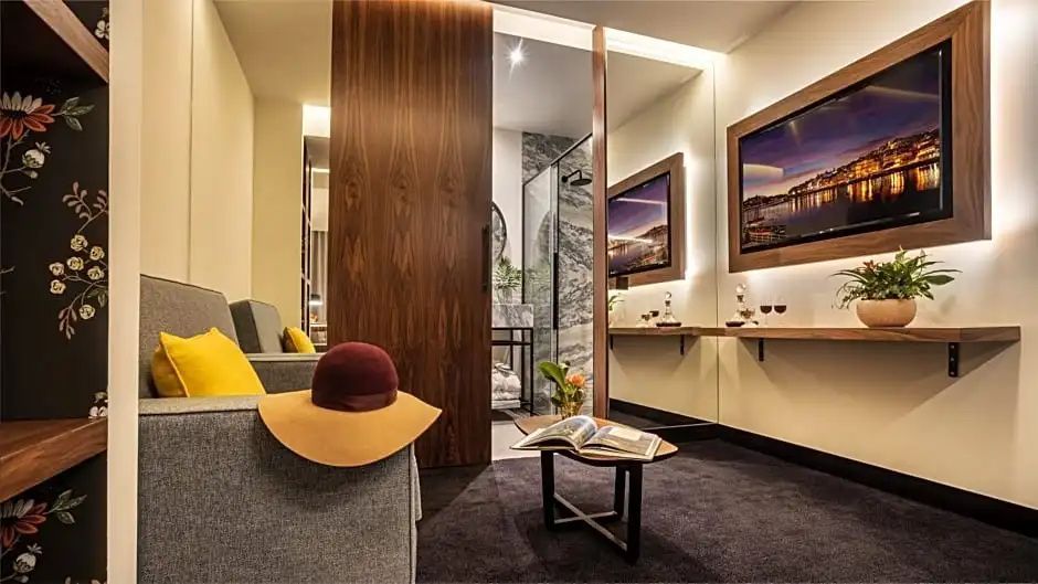 Wohnraum der Suite mit Blick auf das Badezimmer hinter einer Holztür.