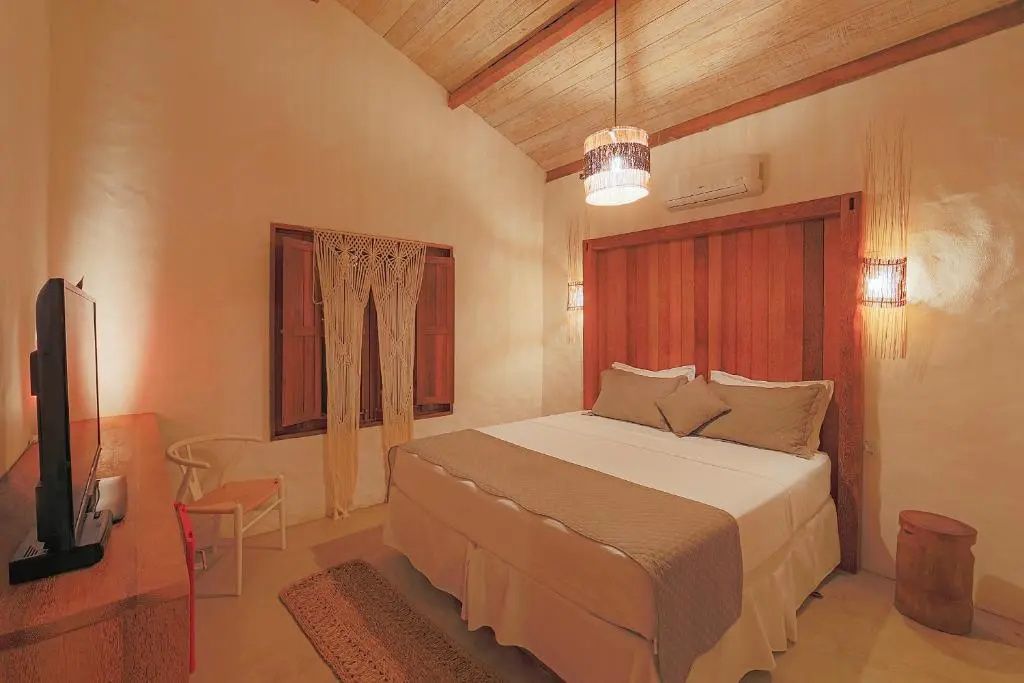 Schlafzimmer mit großem Doppelbett, hölzerner Kopfteilwand und Schrägdach aus Holz.