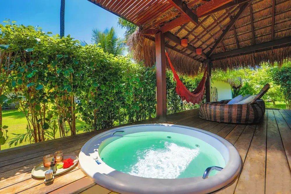 Ein runder Whirlpool mit sprudelndem Wasser auf einer Holzterrasse im Grünen.