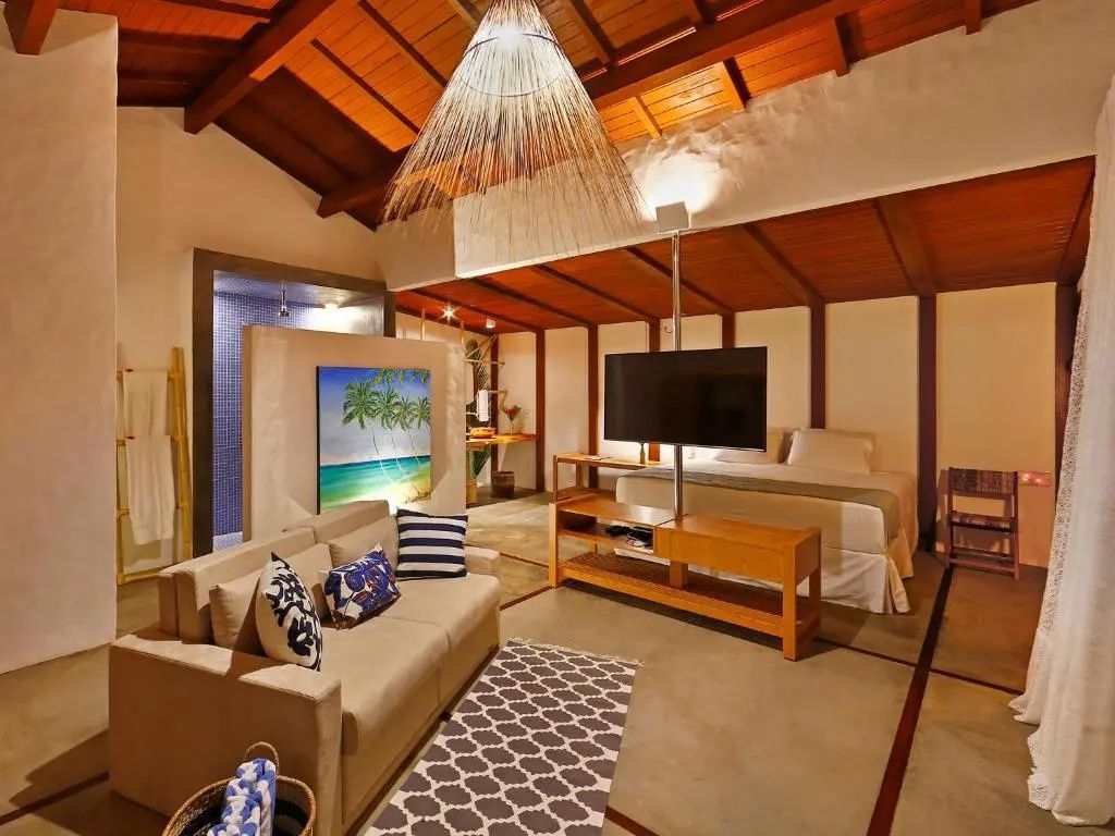 Offener Schlafbereich und Wohnbereich in einem Bungalow mit Holzdecke und Sofa.