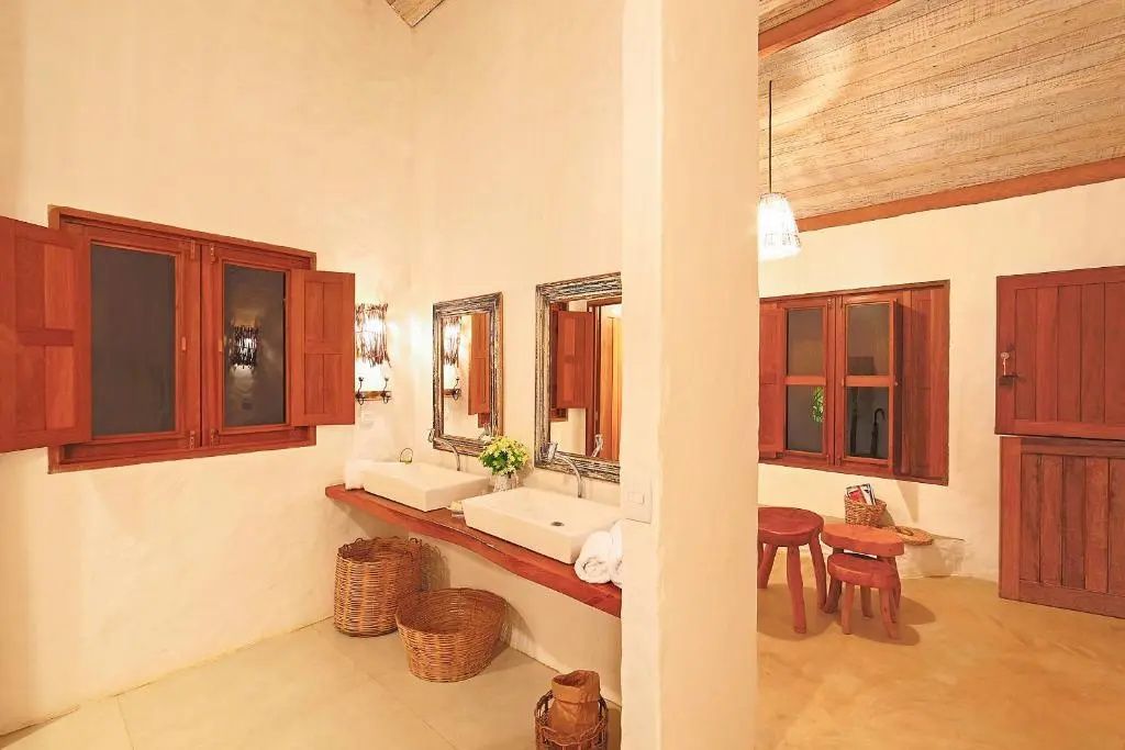 Badezimmer mit zwei Aufsatzwaschbecken auf einer Holzplatte und Holzfensterläden.