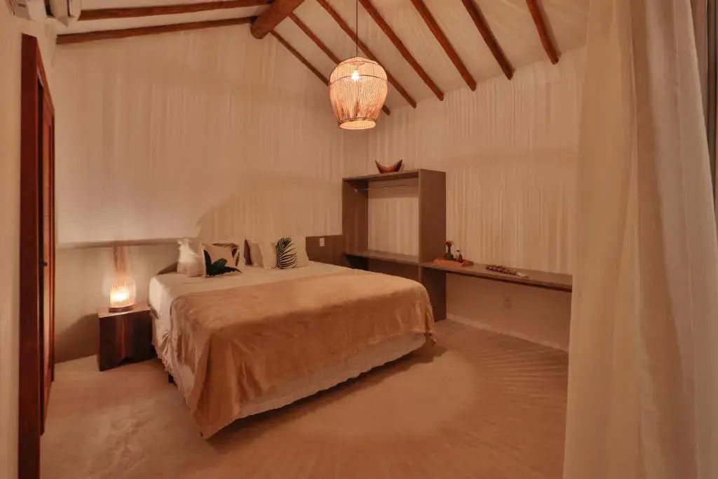 Schlafzimmer mit Doppelbett, Holzdeckenträgern, einer Stricklampe und offenen Regalen.