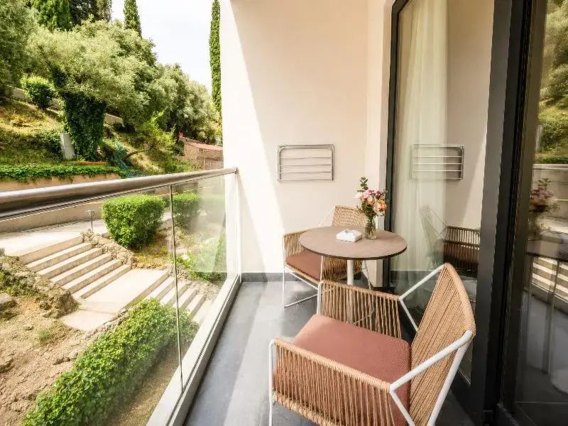 Möblierter Balkon mit zwei Stühlen, kleinem Tisch und Blick auf die grüne Gartenanlage.