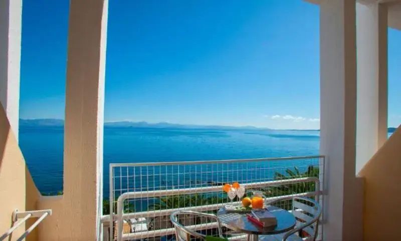 Aussicht vom Balkon mit Tisch und Stühlen auf das blaue Meer unter blauem Himmel.