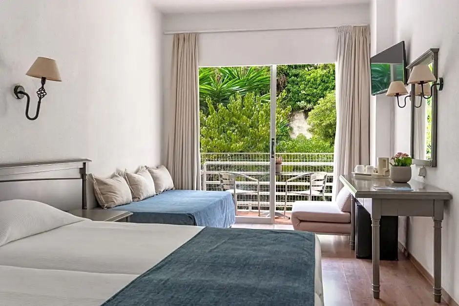 Helles Hotelzimmer mit Tagesbett und Balkontür mit Blick ins Grüne.