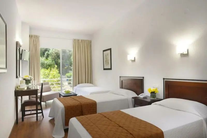 Helles Mehrbettzimmer mit drei Einzelbetten und Blick ins Grüne.
