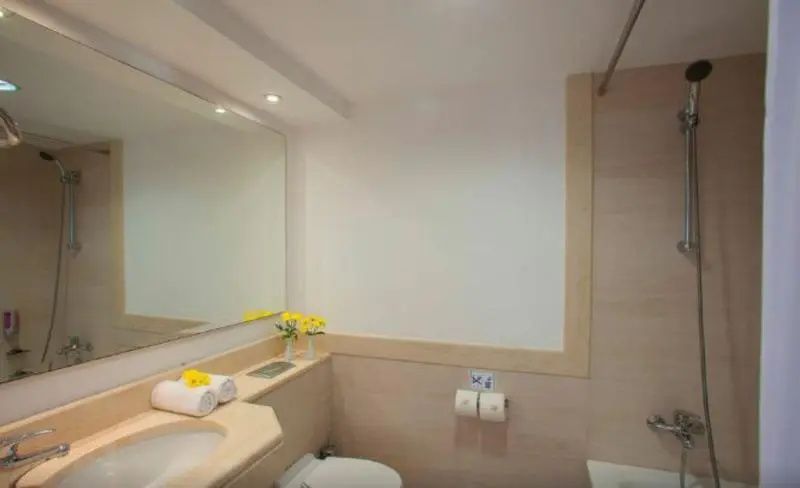 Badezimmer mit Waschtisch, Wandspiegel, Toilette und hellen Fliesen.