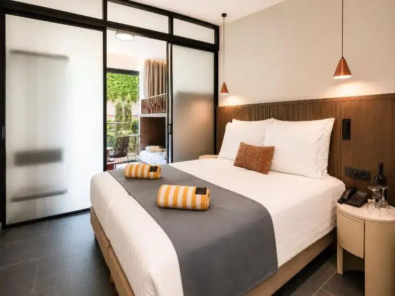 Doppelbett im hellen Hotelzimmer mit Schiebetür zum angrenzenden Kinderbereich.