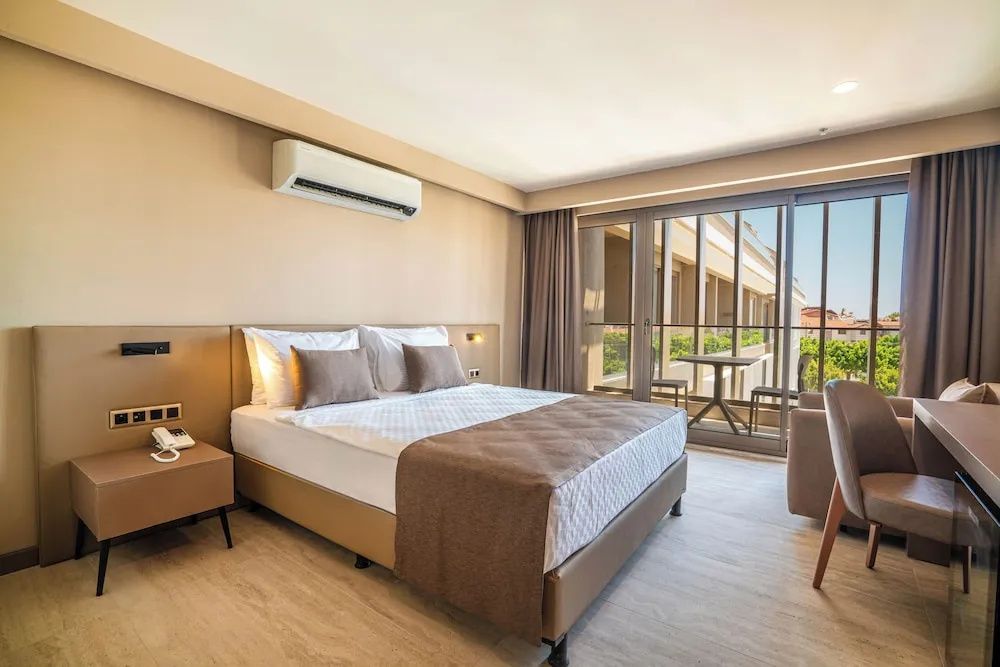 Doppelbett im Hotelzimmer mit brauner Tagesdecke und Zugang zum Balkon.
