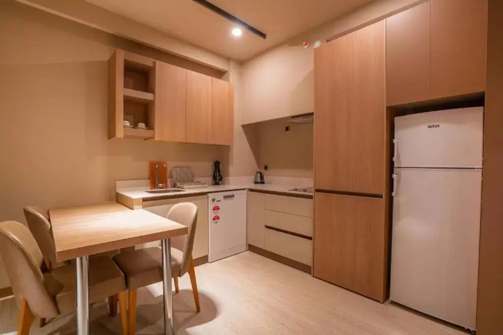 Moderne Küchenzeile in der Suite mit Kühlschrank, Spülmaschine und kleiner Essecke.