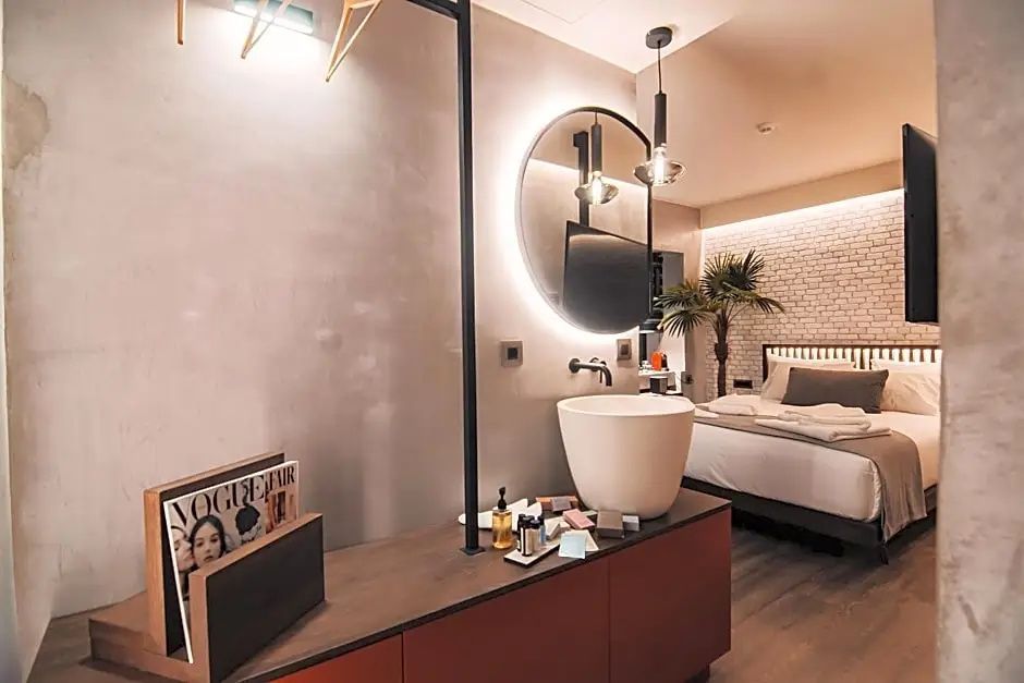 Blick in ein Hotelzimmer mit Waschtisch im Vordergrund und einem Doppelbett hinten