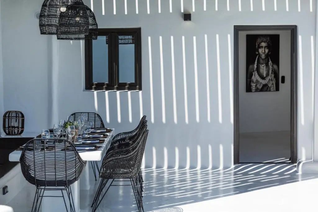 Gedeckter Esstisch auf einer überdachten Terrasse mit Lichteinfall durch Holzlamellen