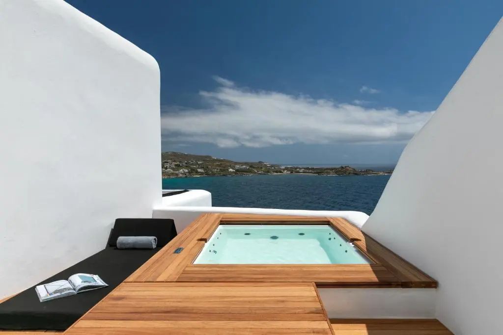 Whirlpool auf einer Holzterrasse mit Blick auf das Meer und den blauen Himmel.