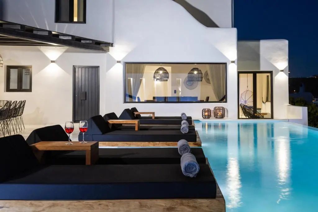 Beleuchtete Außenanlage bei Dämmerung mit Pool und weißer Fassade.