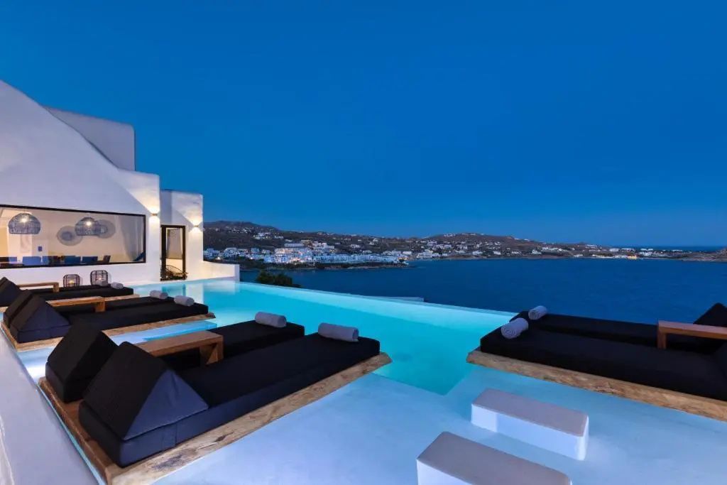 Infinitypool mit schwarzen Liegen bei Dämmerung und Blick auf das Meer.