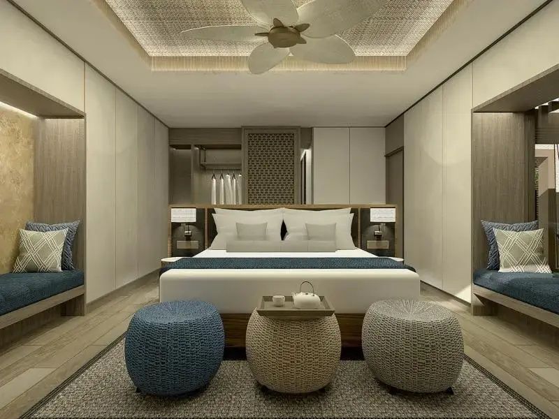Schlafzimmer mit Doppelbett, weißer Bettwäsche und zwei blauen Sitzhockern.