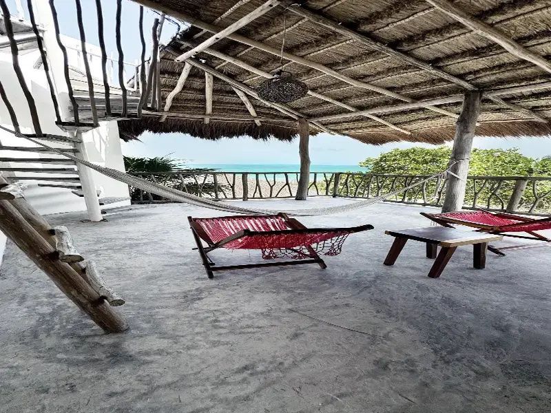Überdachte Terrasse mit Reetdach, Hängematte und freiem Blick auf das türkisfarbene Meer.