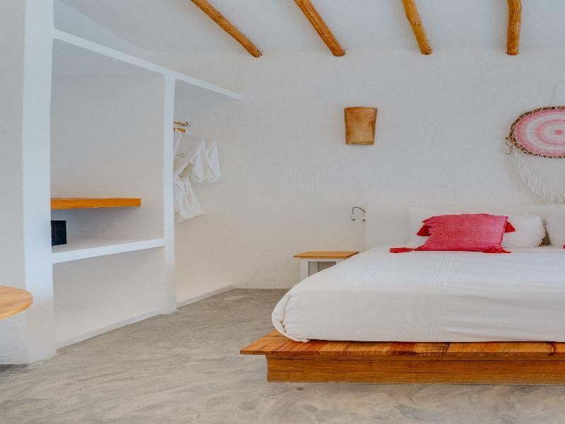 Schlafzimmer mit einem niedrigen Bett aus Holz und eingebauten weißen Regalen.