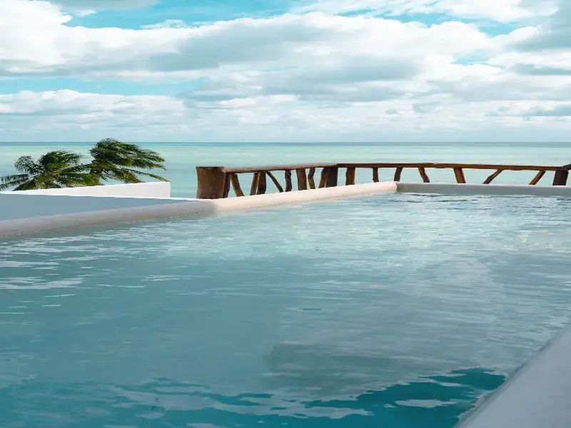 Ein kleiner Pool auf einer Terrasse mit Holzgeländer und freiem Blick auf das klare Meer.
