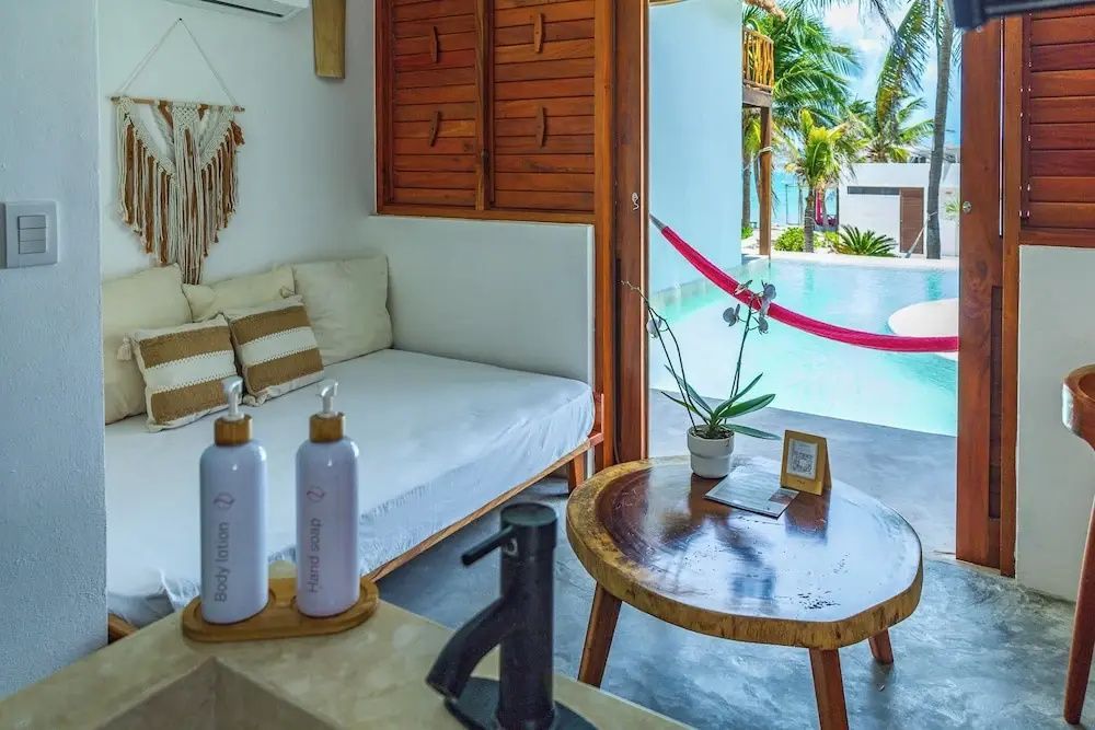 Sitzbereich im Zimmer mit Blick auf den Außenbereich und einen Pool mit rosa Hängematte.