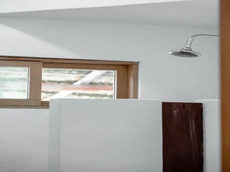 Moderne Dusche mit verchromtem Duschkopf und weiß verputzten Wänden im Badezimmer.