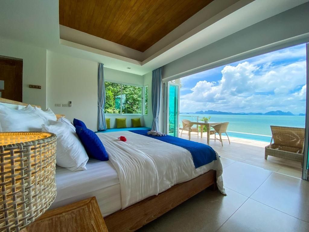 Schlafzimmer mit Holzdecke, großem Bett und Blick auf die Terrasse und den Ozean.