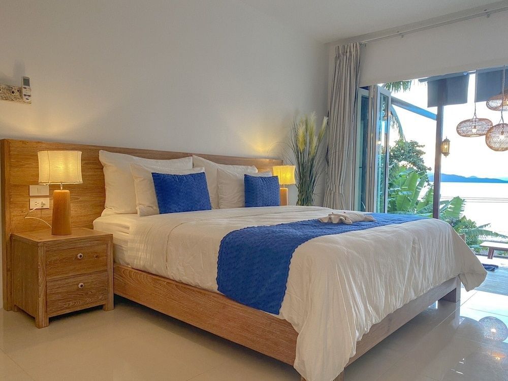 Schlafzimmer mit Blick durch weit geöffnete Türen auf die tropische Natur.