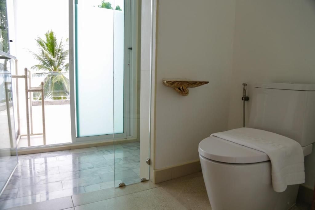 Moderne Toilette und verglaste Duschkabine in einem hell gefliesten Badezimmer.