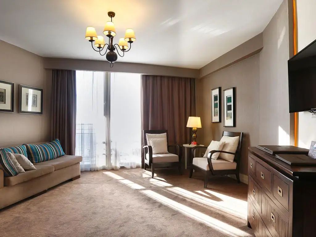 Sitzbereich in einem Hotelzimmer mit Sofa, Sesseln und bodentiefen Fenstern.