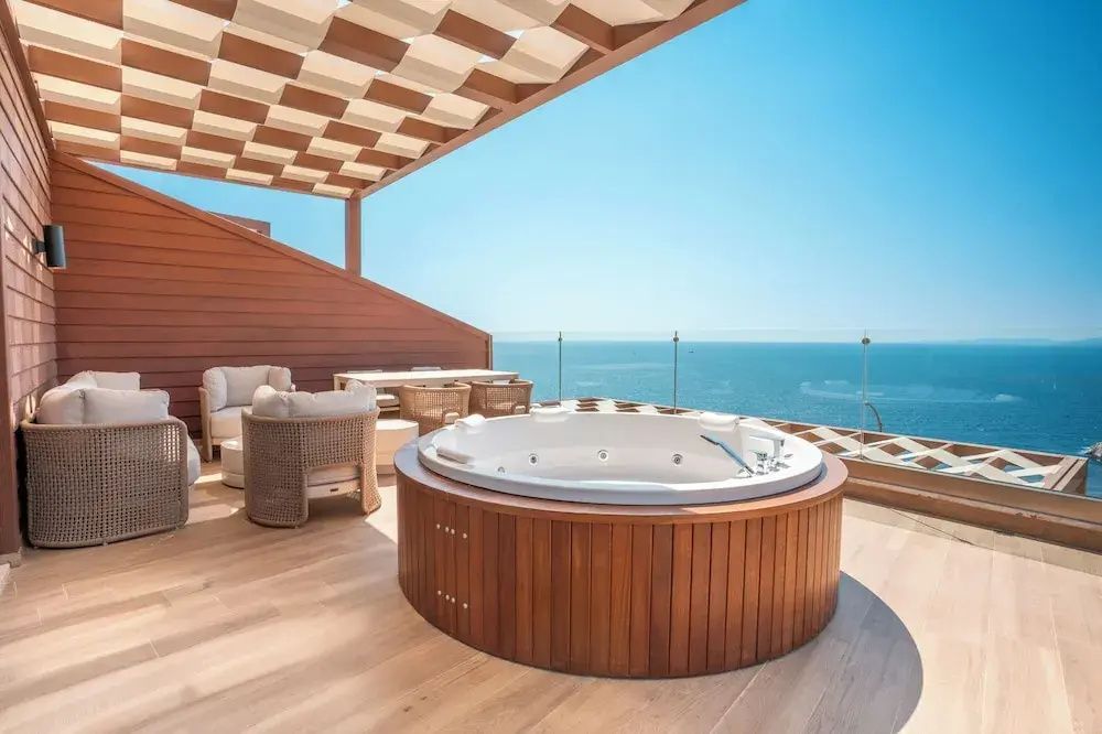 Whirlpool auf einer Holzterrasse mit weitem Blick über das offene Meer.