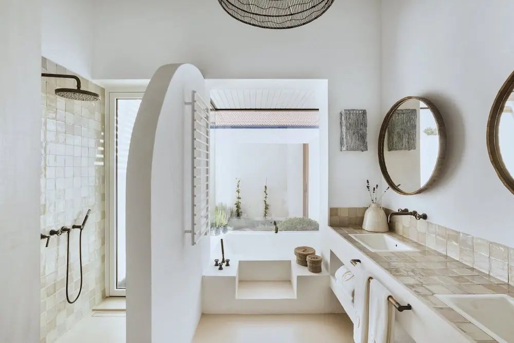 Badezimmer in Weißtönen mit integrierter Badewanne und Waschtisch.