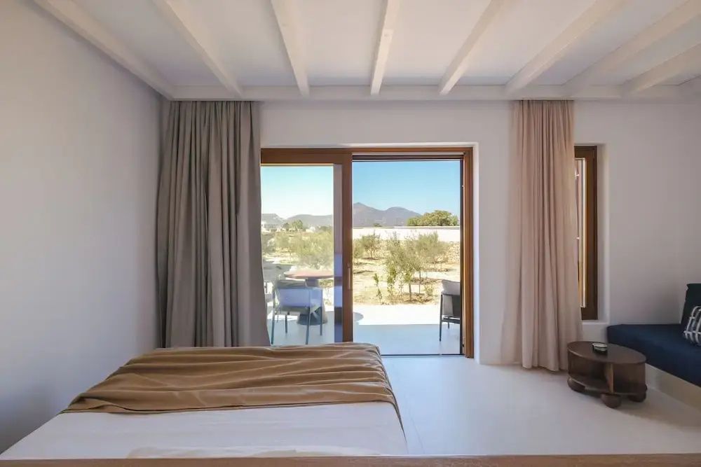 Schlafzimmer mit Blick durch eine Glasschiebetür auf die Terrasse und Hügel.